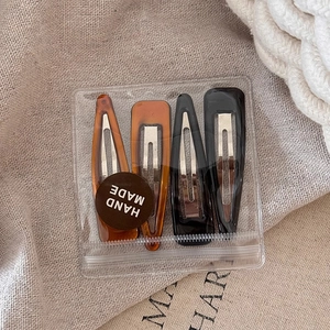 Détail d'un lot de quatre barrettes en résine ambre et noir faites à la main en sachet