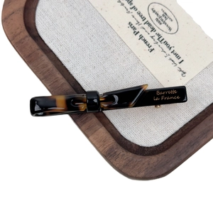 Elegant tortoise shell barrette with gold engraving on a rustic walnut tray