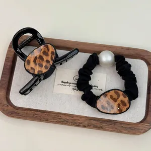 Elegant leopard print hair claw clip and pearl scrunchie set on a decorative wooden tray