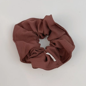 Close-up of a deep brown fabric scrunchie with textured suit material and white label