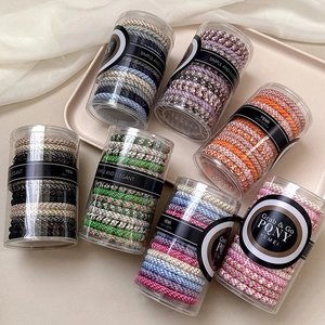 Colorful high elasticity braided hair ties set in a transparent jar with silk background