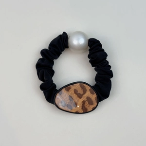 Detail of black pleated scrunchie with large white pearl and oval leopard print accent