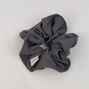 Detailed macro shot of dark grey scrunchie fabric with a white Hand Made woven label