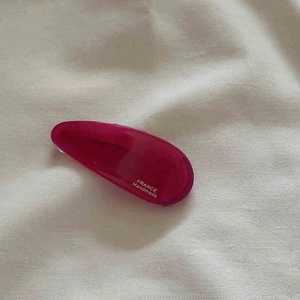 Détail d'une pince à cheveux goutte fuchsia avec inscription France Handmade blanche