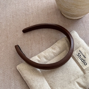 Detailed view of wide dark brown leather headband with a smooth padded texture