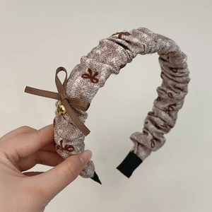 Détail d'un serre-tête en tissu rayé avec un nœud marron et un pendentif cœur doré
