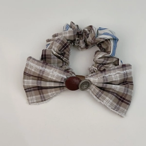 Close-up of checkered bow scrunchie featuring vintage buttons and striped fabric detail
