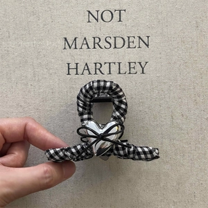 Checkered fabric shark hair clip with silver heart and bow accent in a stylish hand-held view