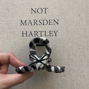 Detailed view of black and white gingham fabric hair claw with silver heart and bow accent