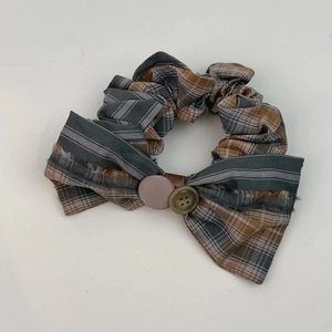 Detail of vintage British plaid scrunchie with bow decoration and retro button center