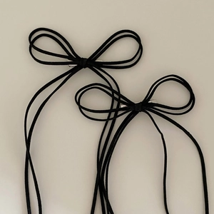 Set of two black suede bow hair clips in minimalist Korean style on a neutral background