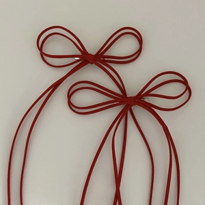 Detail view of a pair of red suede bow hair clips with silver metal spring fasteners