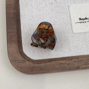 Detail shot of mini tortoiseshell hair claw clip made of amber resin on fabric background
