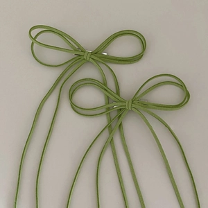 Detail of green faux suede bow hair clips with silver metal alligator grip fasteners