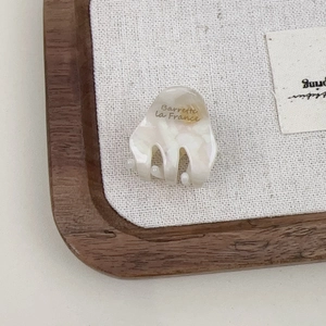 Detail of a mini acetate hair claw with marble texture and Barrette La France gold lettering