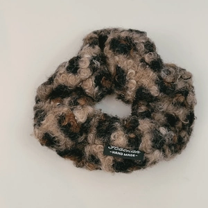 Close-up of leopard print faux shearling scrunchie with handmade woven brand label