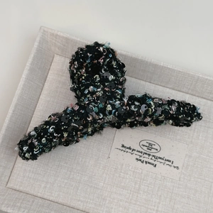 Détail de la pince à cheveux en tweed avec fils colorés et paillettes noires brillantes