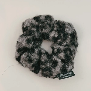 Detail view of handmade lamb wool leopard scrunchie with woven Haokan brand label