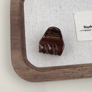 Close-up of a brown acetate hair claw featuring golden Barrette la France lettering