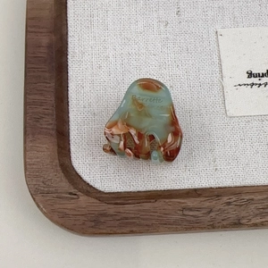 Close-up of mini acetate hair claw clip with marble texture and France gold logo