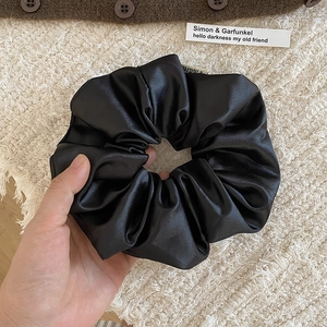 Gros plan détaillé du chouchou en satin noir brillant avec de riches plis de tissu