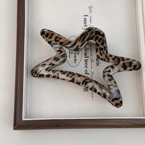 Detail shot of a star-shaped leopard print hair claw clip with a strong golden metal spring