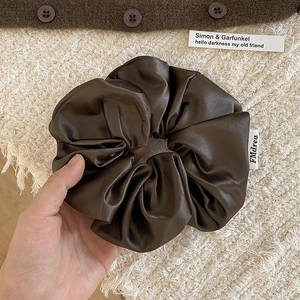 Détail d'un grand chouchou en satin marron chocolat avec étiquette FMdrea et aspect soie