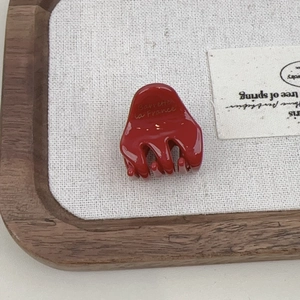 Close-up of a red acetate claw clip with Barrette la France engraving on a rustic tray
