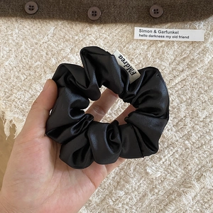 Détail d'un grand chouchou en satin noir aux plis souples et texture de qualité