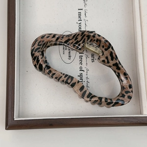 Close-up of leopard print hair claw clip showing glossy texture and golden metal spring