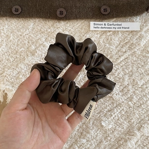 Gros plan détaillé d'un chouchou en satin marron foncé avec étiquette de marque