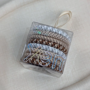 Set of thick braided elastic hair ties in brown and beige tones in a clear gift box