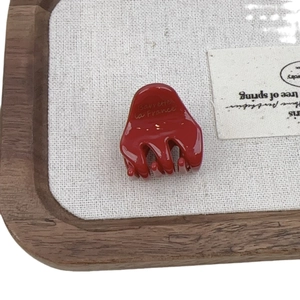 Glossy red French acetate hair claw clip with Barrette la France logo on wooden tray