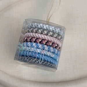 Detailed view of assorted woven elastic hair ties in a transparent portable gift box