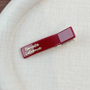 Détail de la barrette bordeaux avec texte doré Barrette La France sur tissu beige