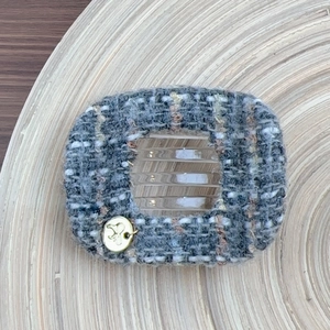 French tweed hair claw in dark grey with star charm on a rustic wooden tray