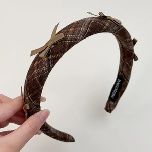 Detail view of a vintage plaid bow headband featuring handmade texture and stitching