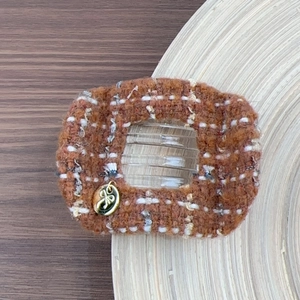 Close-up of caramel tweed hair claw with star tag and bow relief on gold charm