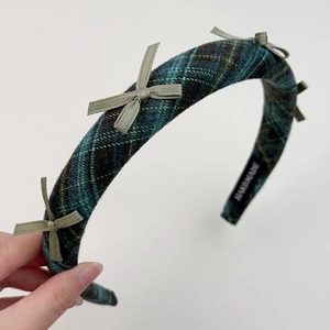 Detailed texture of green plaid wool headband with handmade label and bowknots