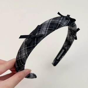 Detail of grey plaid wool headband with black bows and handmade label on inner side