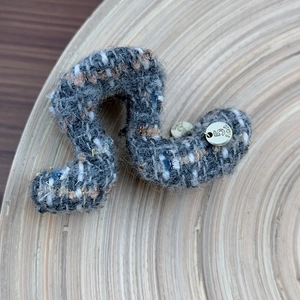Macro shot of S-shaped tweed hair claw clip with golden Paris number five metal charm