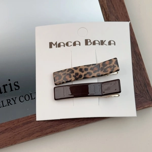 Detail view of leopard print and dark brown hair clips set on white brand card
