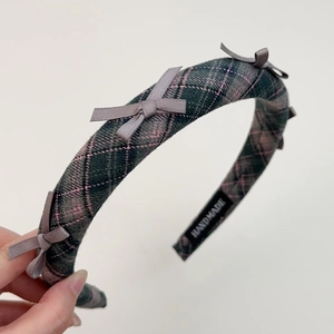 Detailed macro view of handmade green plaid headband with small grey bows and woven label