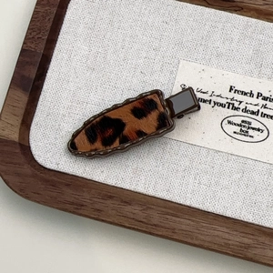 Close-up of leopard print hair clip with vintage animal texture on white fabric