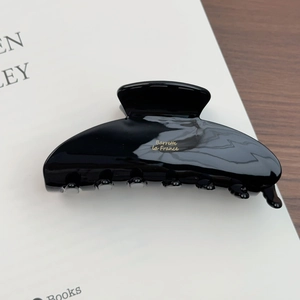 Détail d'une pince à cheveux noire brillante en acétate avec logo Barrette La France doré