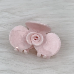 Detail view of the pink marble textured acetate rose flower hair claw clip on white fur