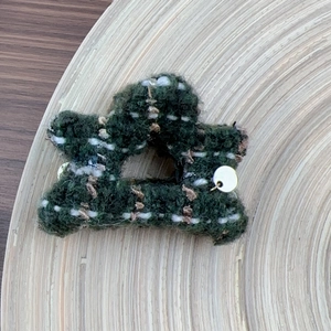 Close-up of green tweed star hair claw clip with silver letter tag on wooden tray