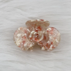Macro shot of rose-shaped acetate hair claw with delicate pink mottled texture