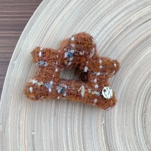Detail of tweed star hair claw with golden letter charm on a wooden tray background