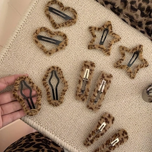 Barrettes à cheveux en peluche léopard en forme de cœur sur fond en tricot